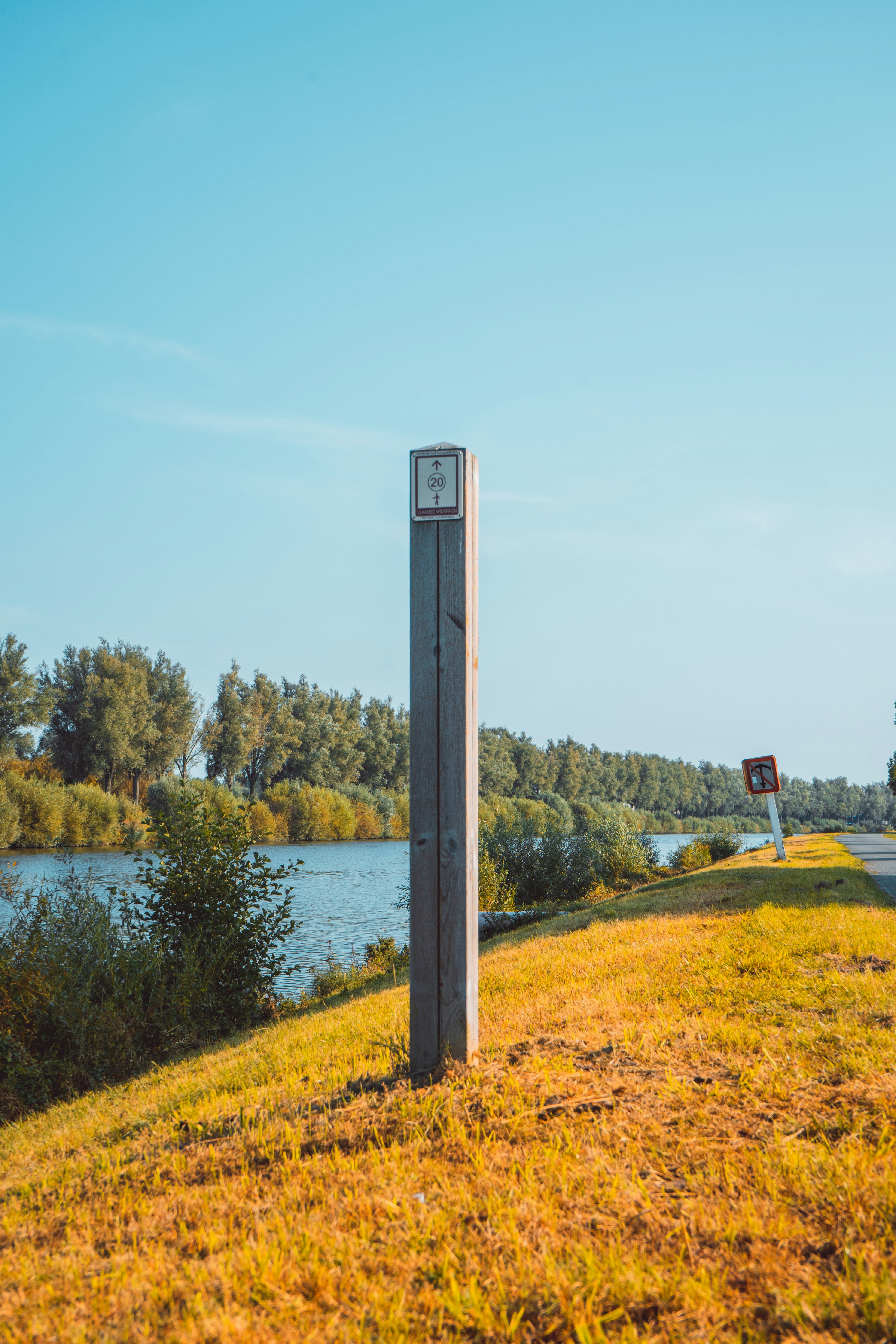a clock sitting on the side of a road next to a river