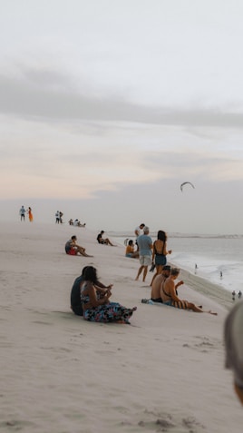 a group of people sitting on top of a sandy beach