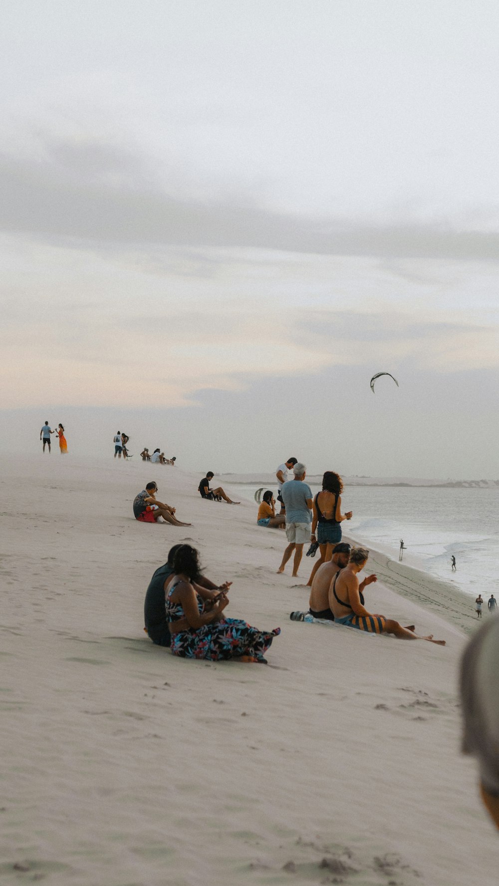 a group of people sitting on top of a sandy beach