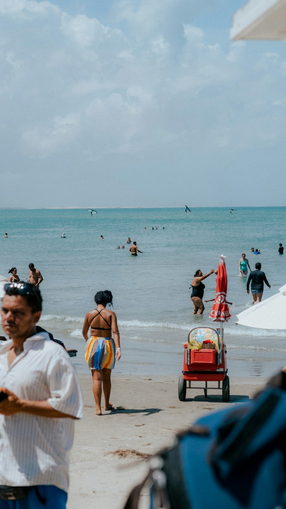 a crowded beach with people walking and swimming