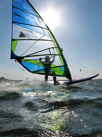 A thrilling moment of windsurfing with a colorful sail cutting through ocean waves.