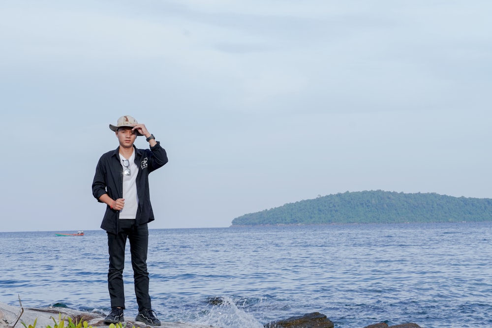 Un uomo in piedi su una roccia vicino all'oceano