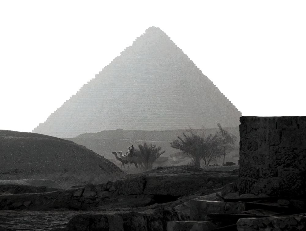 a black and white photo of a pyramid in the desert