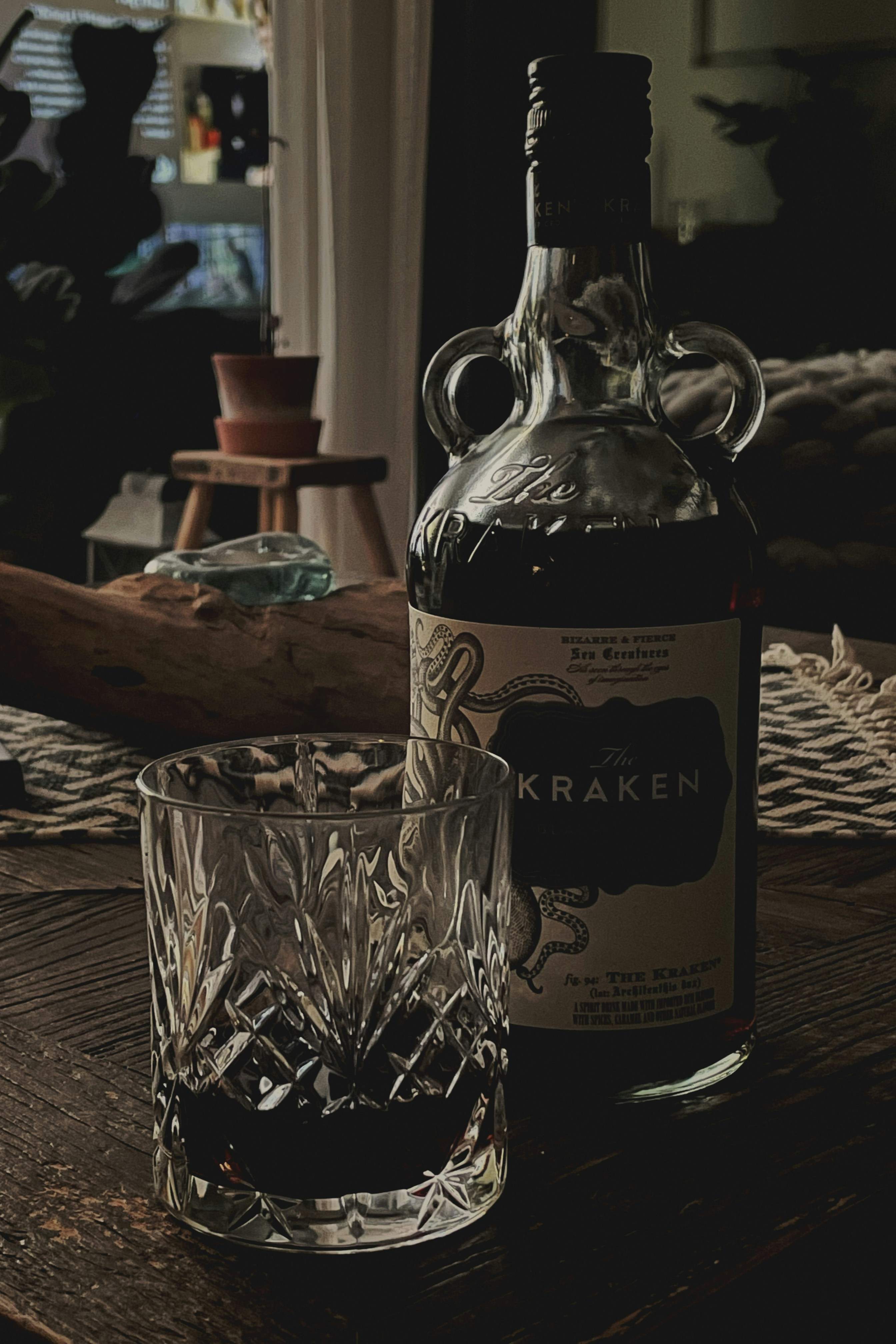 A glass of dark rum on a wooden table.