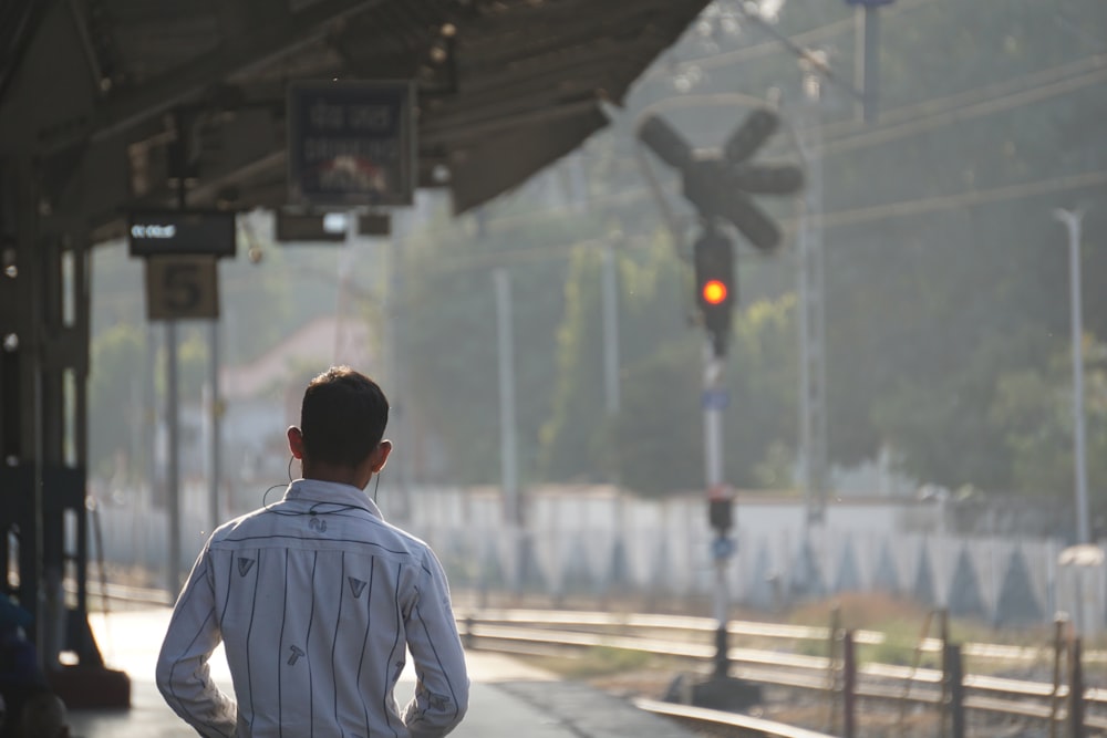 a man standing at a train station waiting for a train