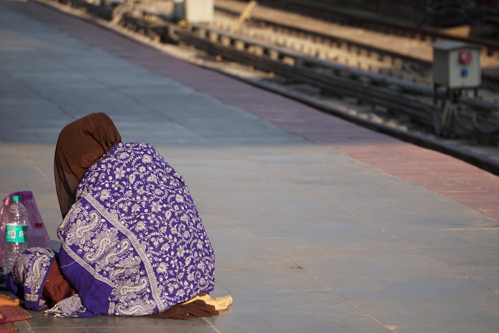 a woman sitting on the ground next to a train track