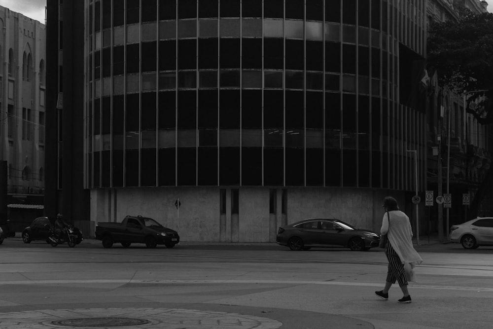 a man walking across a street next to a tall building