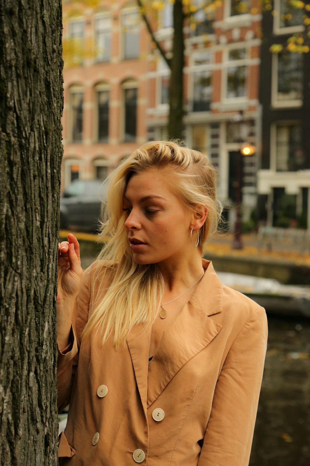 a woman standing next to a tree in front of a building