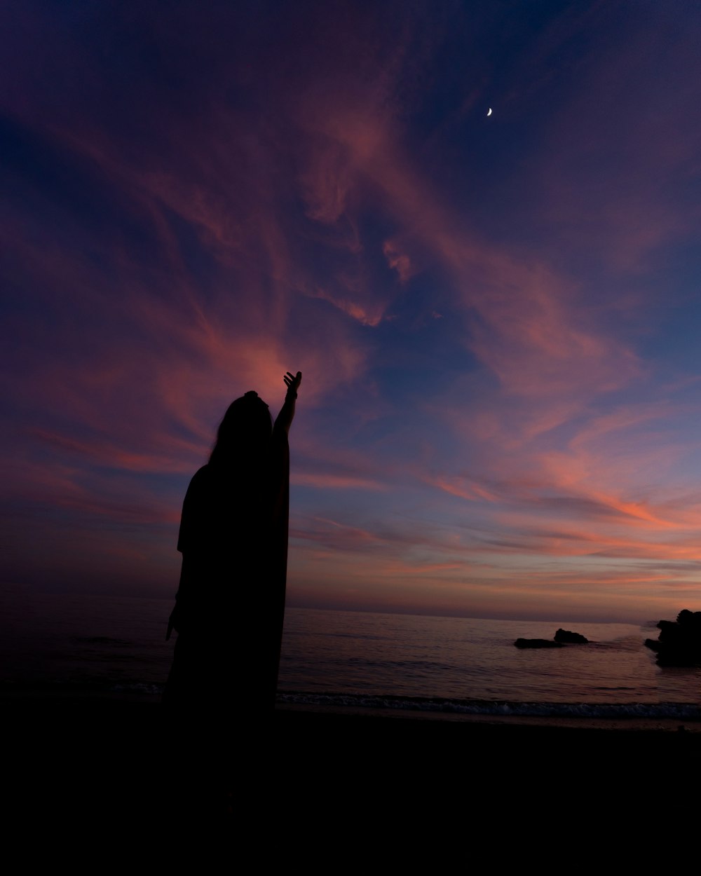 a person standing on a beach with a sunset in the background