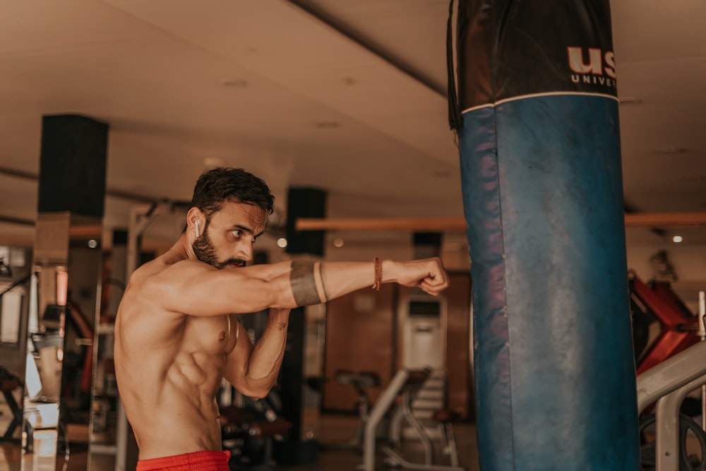 a shirtless man in a gym with a punching bag