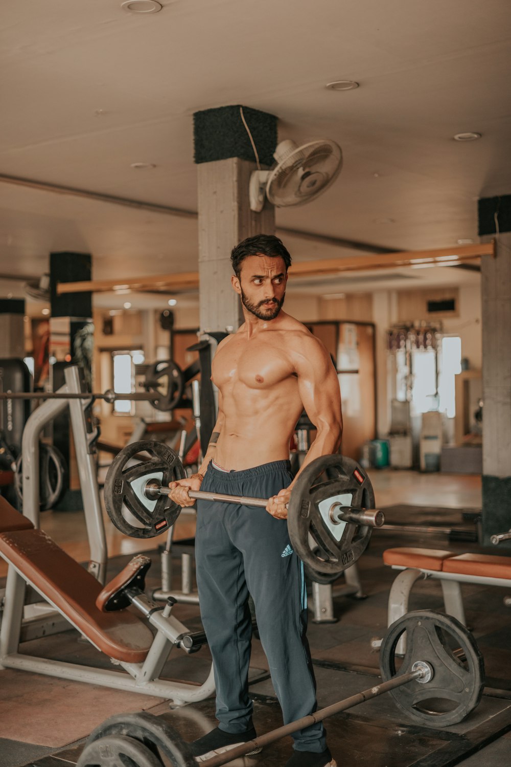 a shirtless man holding a barbell in a gym