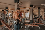 A male fitness influencer mid-workout, lifting weights in a bright gym.