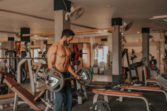 A fit man lifting weights in a gym with focused determination.
