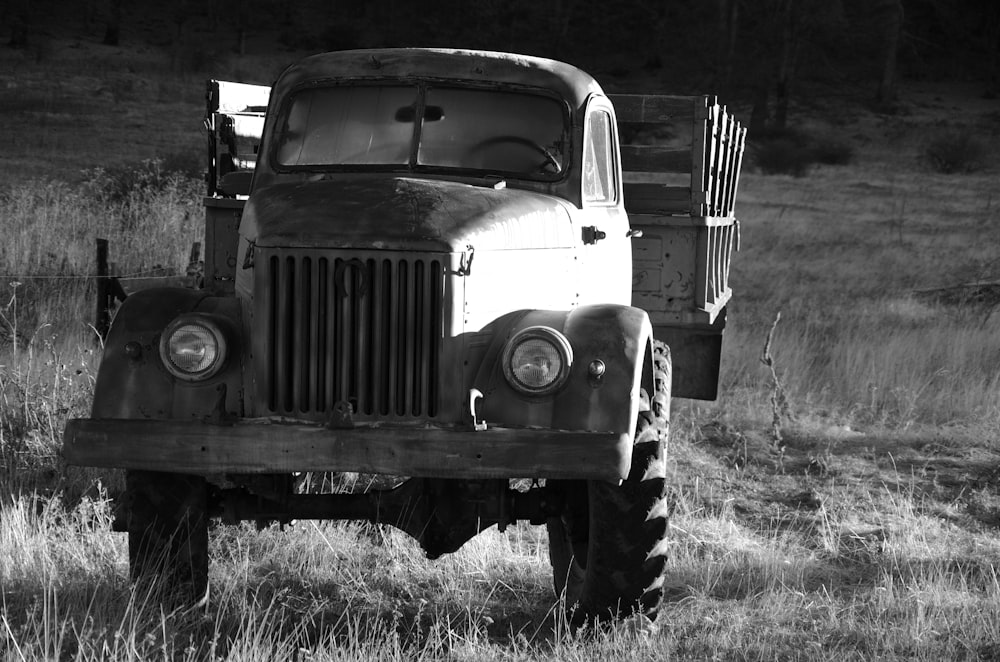 a black and white photo of an old truck in a field