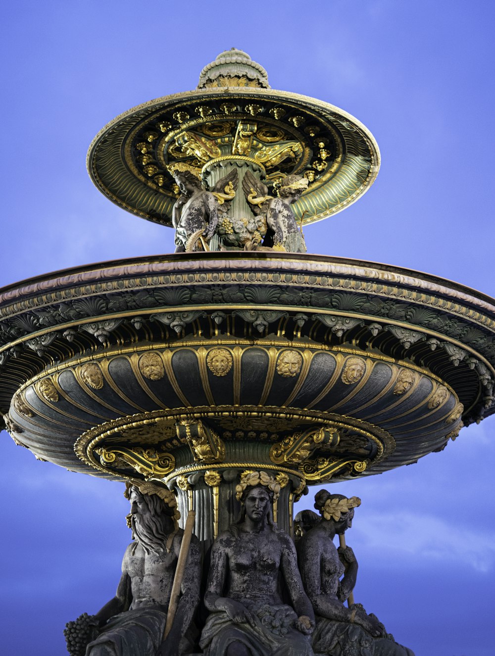 a fountain with statues on top of it against a blue sky