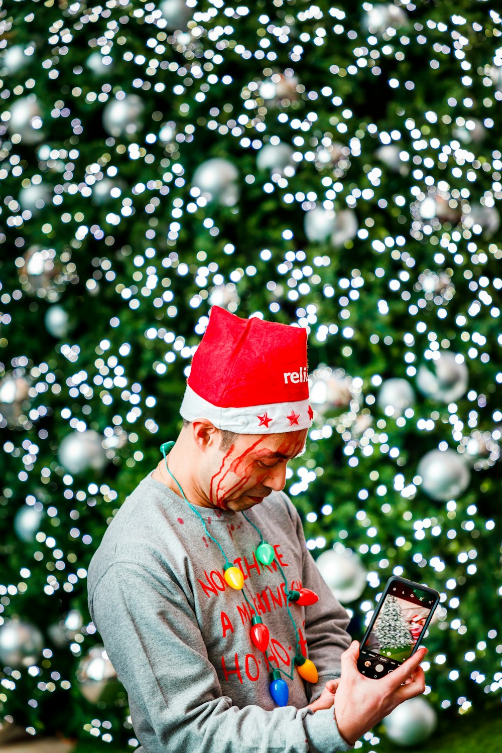 Un homme portant un chapeau de Père Noël tout en regardant un téléphone portable