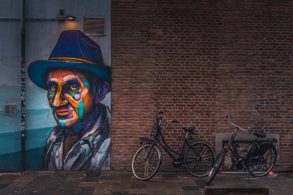 a bicycle parked next to a painting of a man wearing a hat
