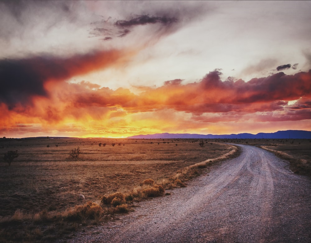 a dirt road with a sunset in the background