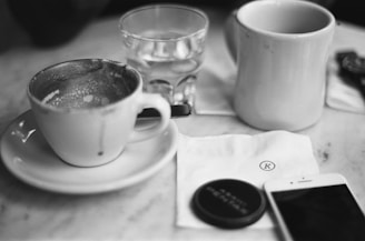 a cup of coffee and a cell phone on a table