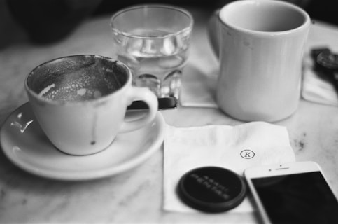a cup of coffee and a cell phone on a table