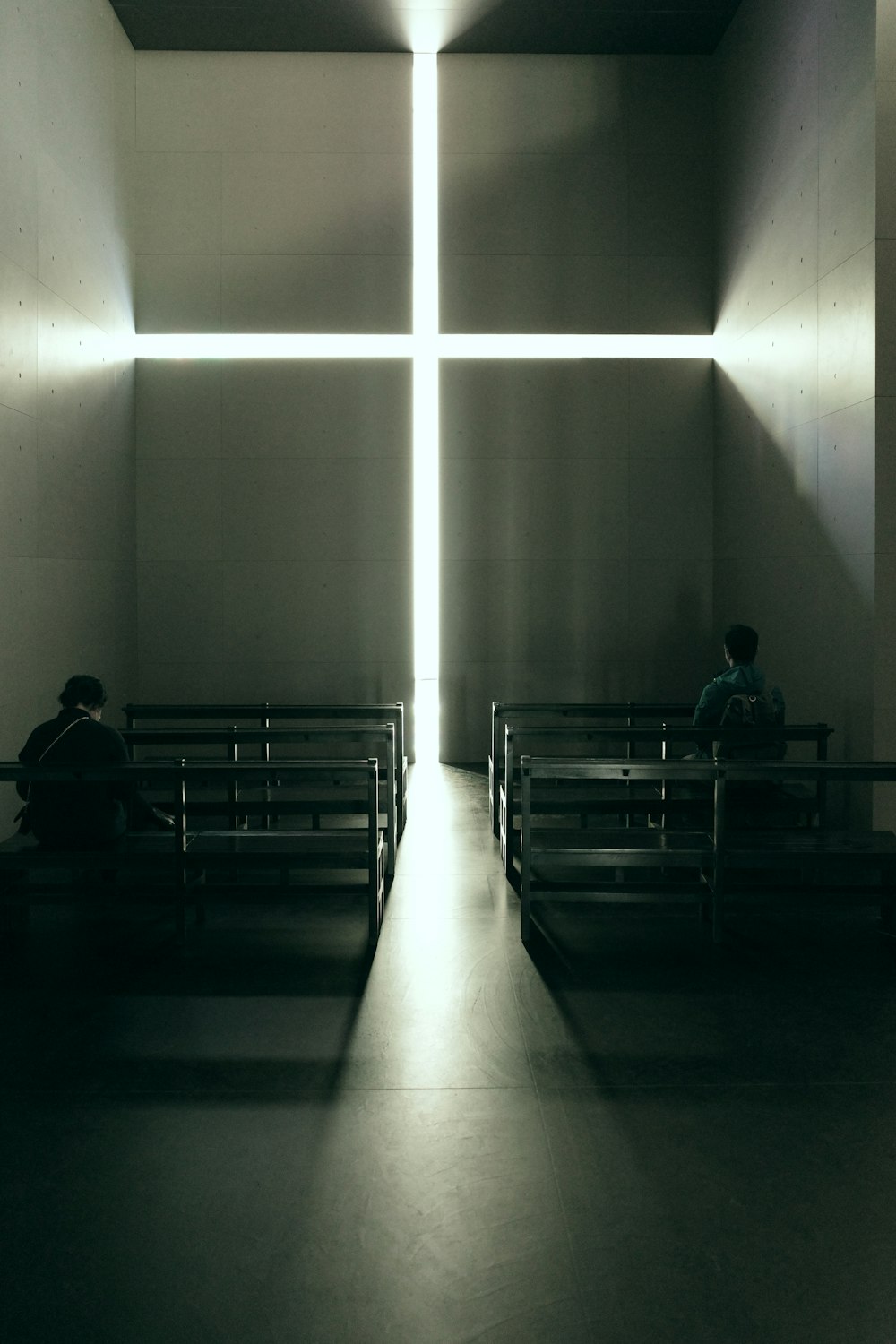 two people sitting on benches in a dimly lit room