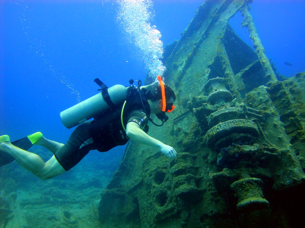 a person in a scuba suit diving next to a ship