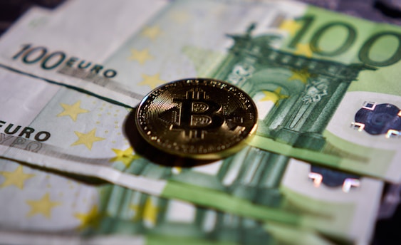 a bitcoin sitting on top of a pile of money