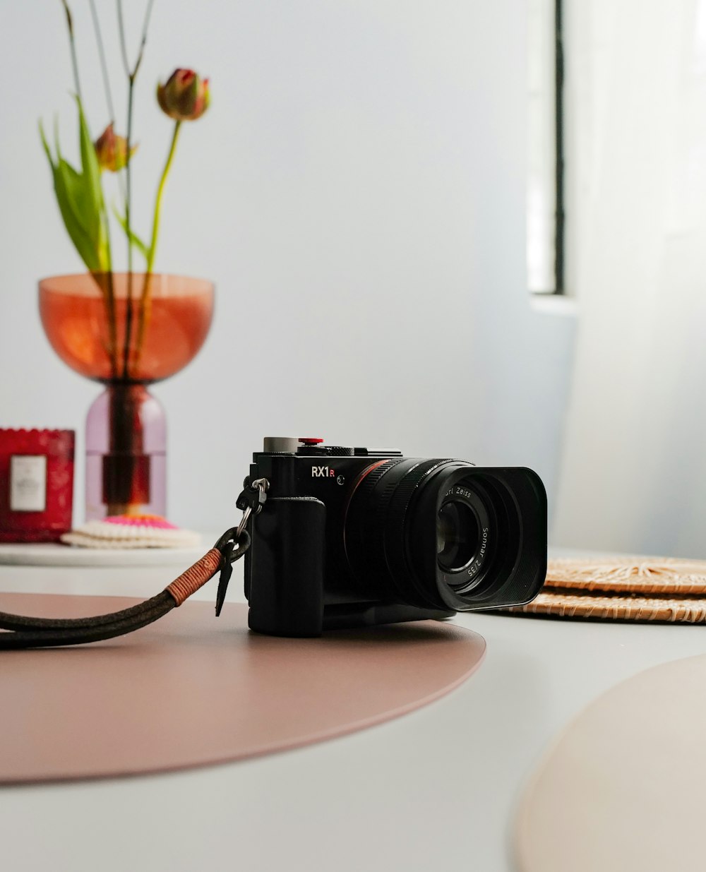 a camera sitting on a table next to a vase with flowers