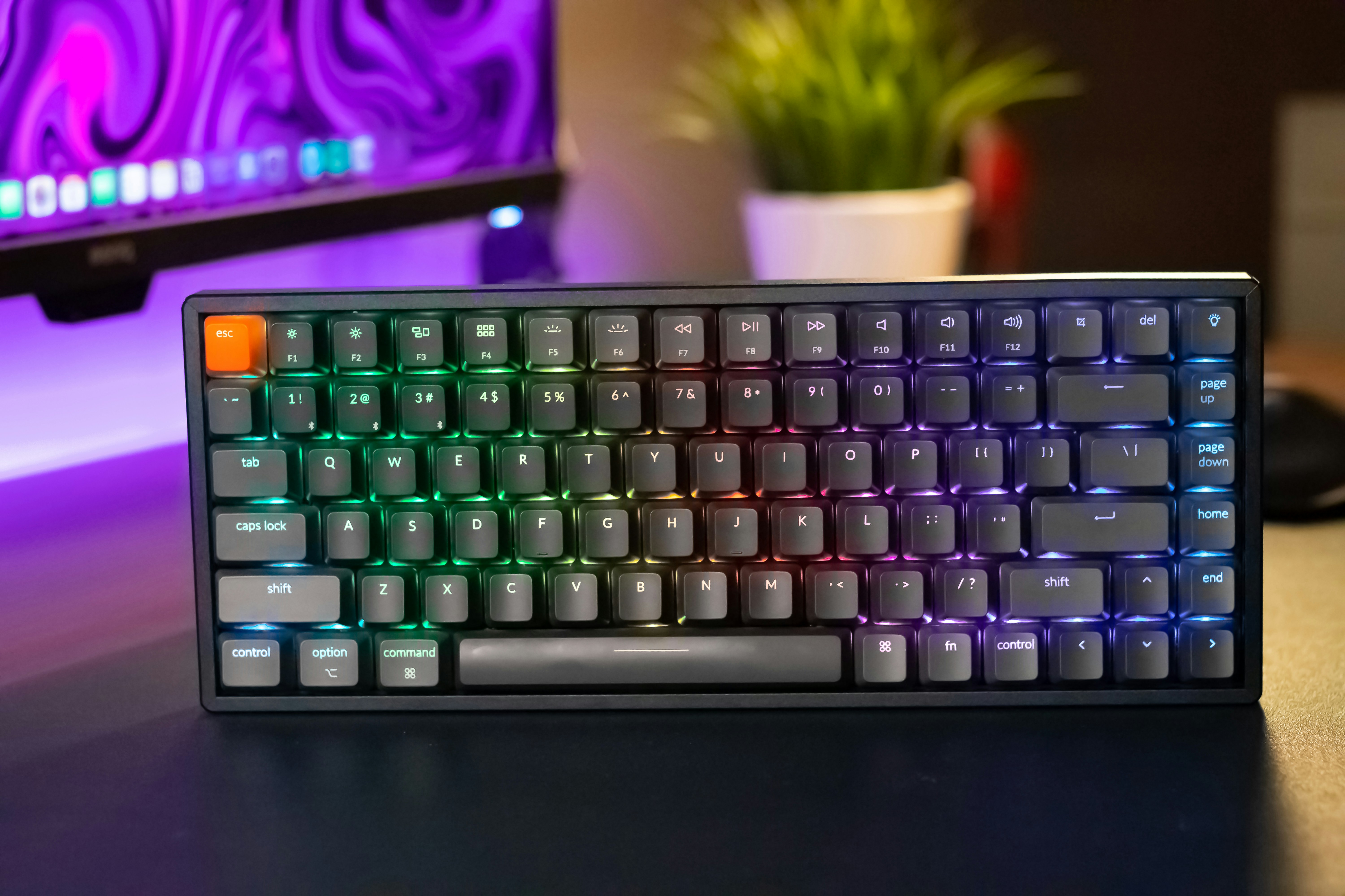 Compact mechanical keyboard with RGB backlight on a wooden desk, top-down view