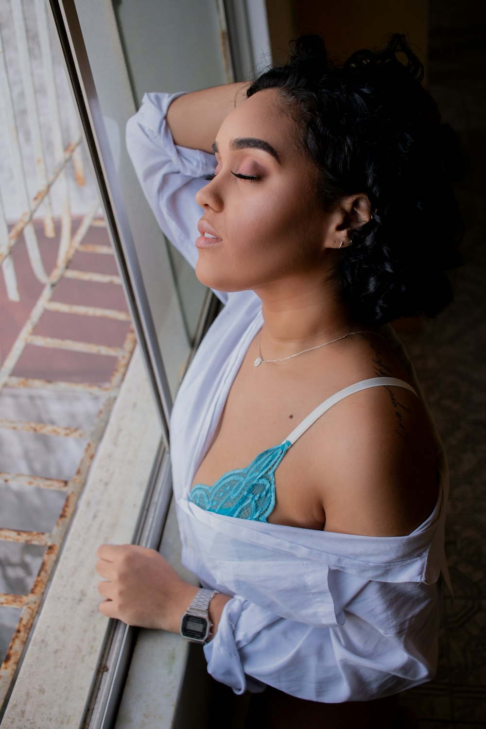 a woman in a white shirt leaning against a window