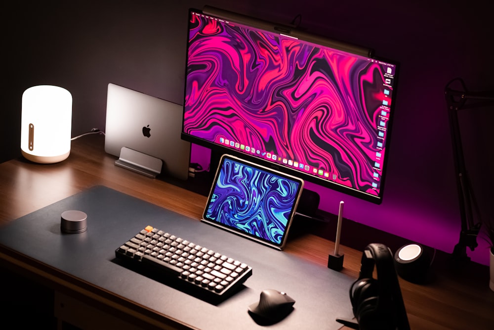 a desk with a laptop, keyboard, mouse and monitor