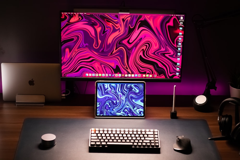 a desk with a laptop, keyboard and monitor