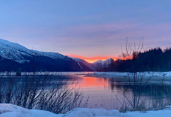 A lake surrounded by snow covered mountains at sunset — Juneau, United States