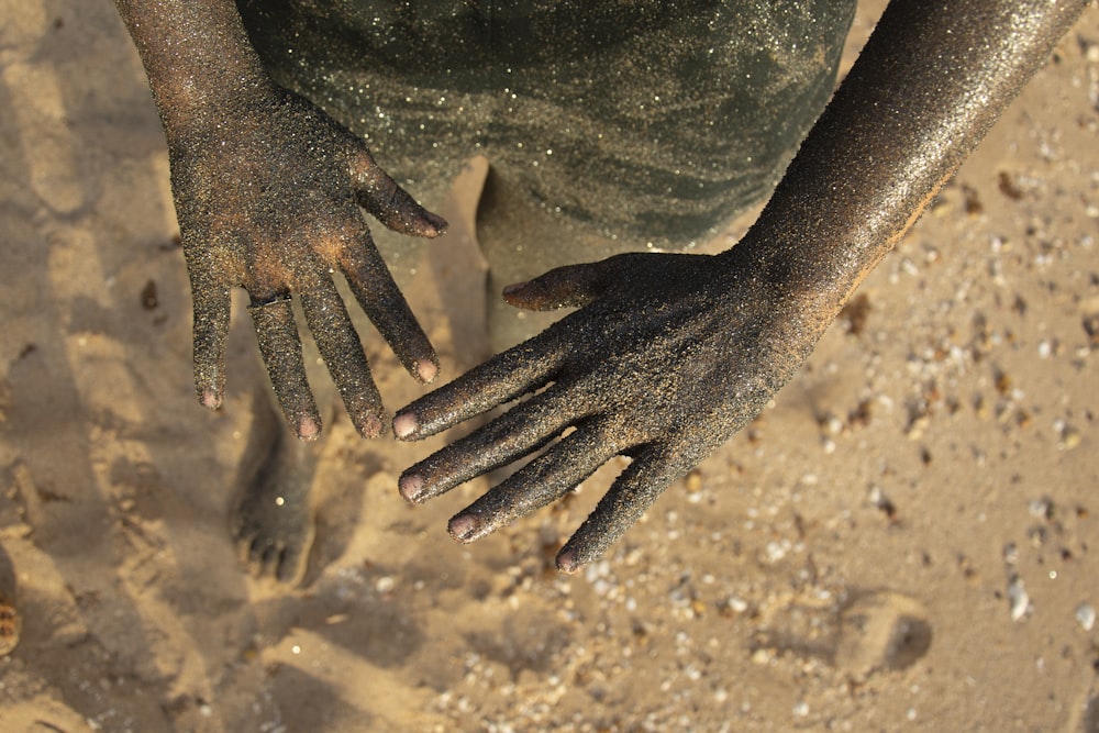 a close up of a person's hands on the sand