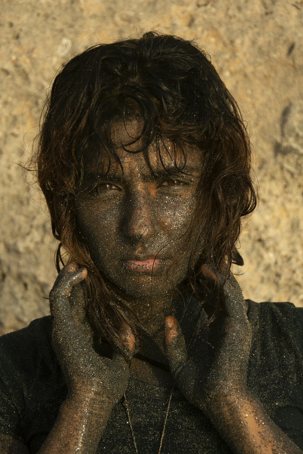 a man covered in mud with his hands on his face