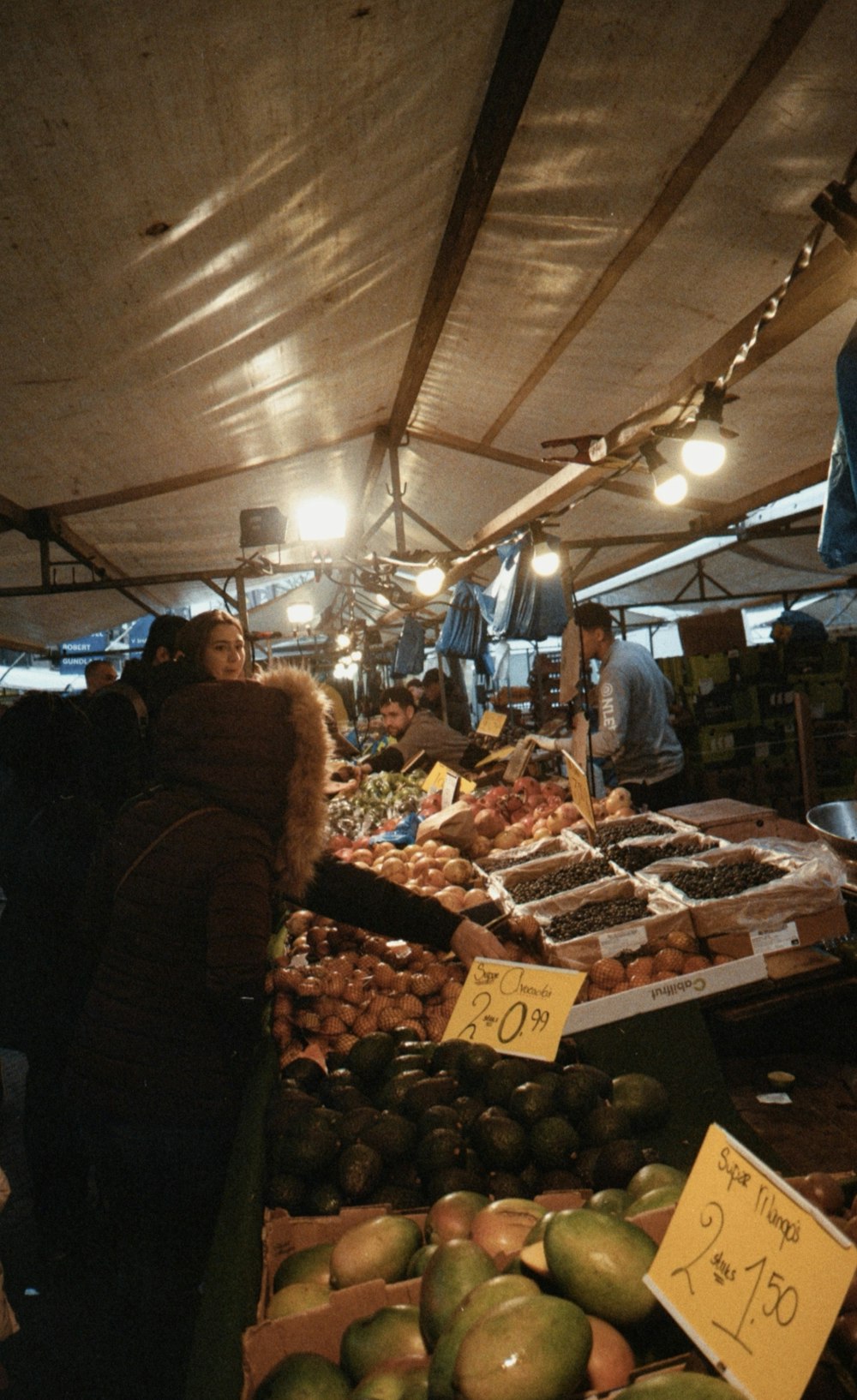 a group of people standing around a fruit stand