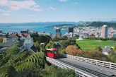 a red train traveling down tracks next to a lush green hillside