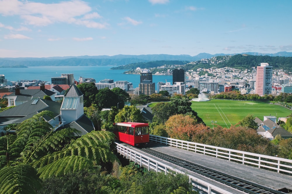 a red train traveling down tracks next to a lush green hillside