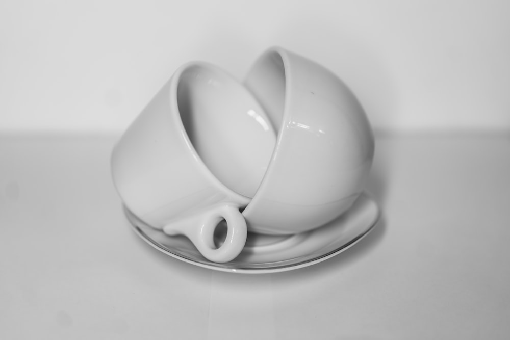 una tazza bianca e un piattino seduti sopra un piattino