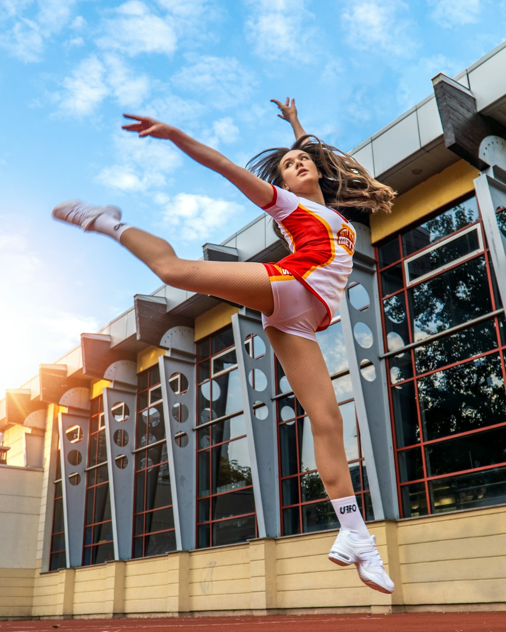 a woman in a red and white uniform jumping in the air