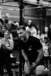 a man squatting in front of a group of people