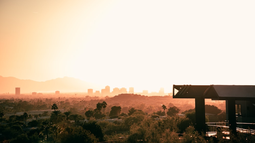 the sun is setting over a city with mountains in the background