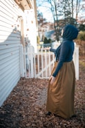 a woman in a blue hoodie is standing outside of a house