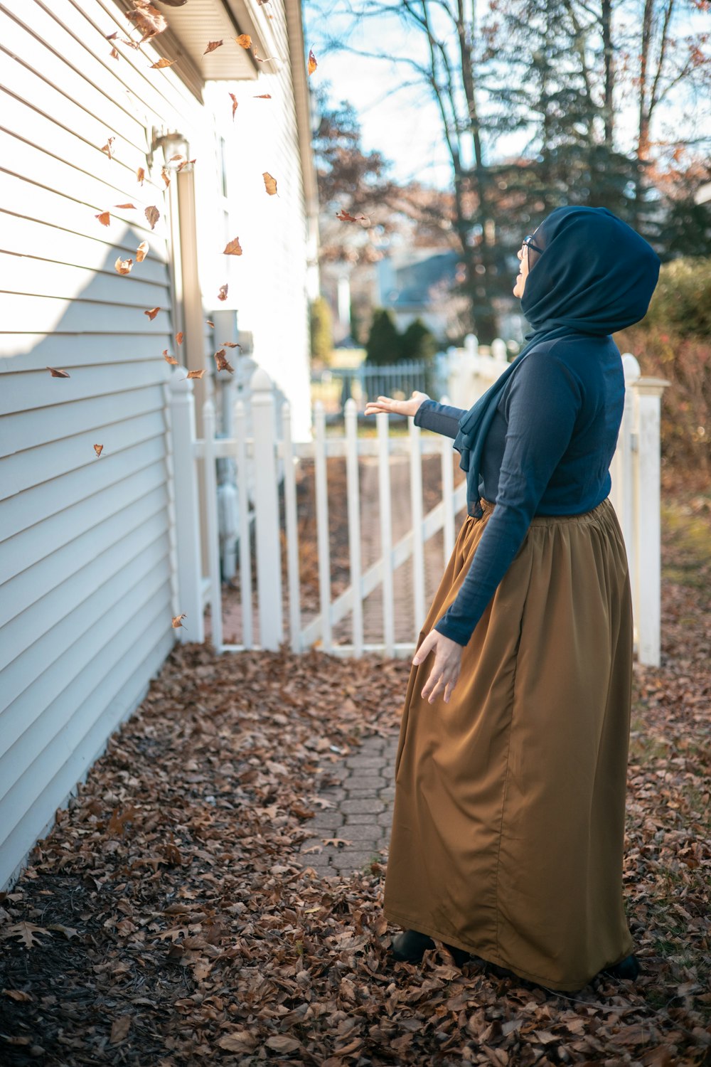 a woman in a blue hoodie is standing outside of a house