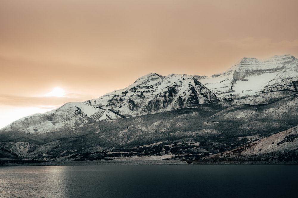 a mountain covered in snow next to a body of water