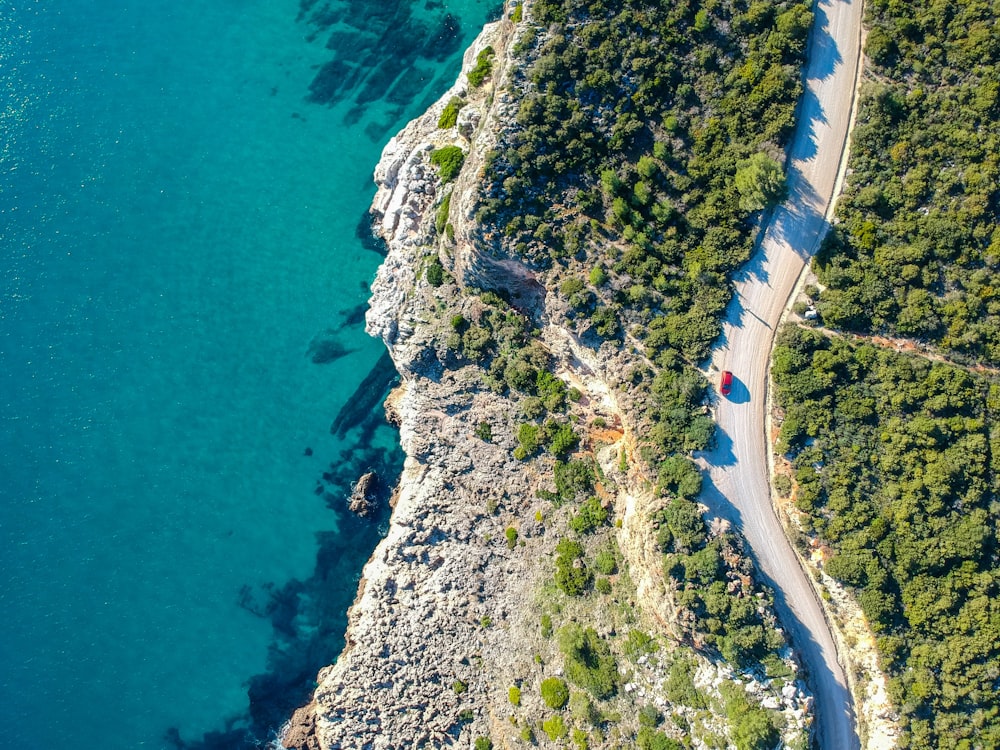 an aerial view of a road next to a body of water