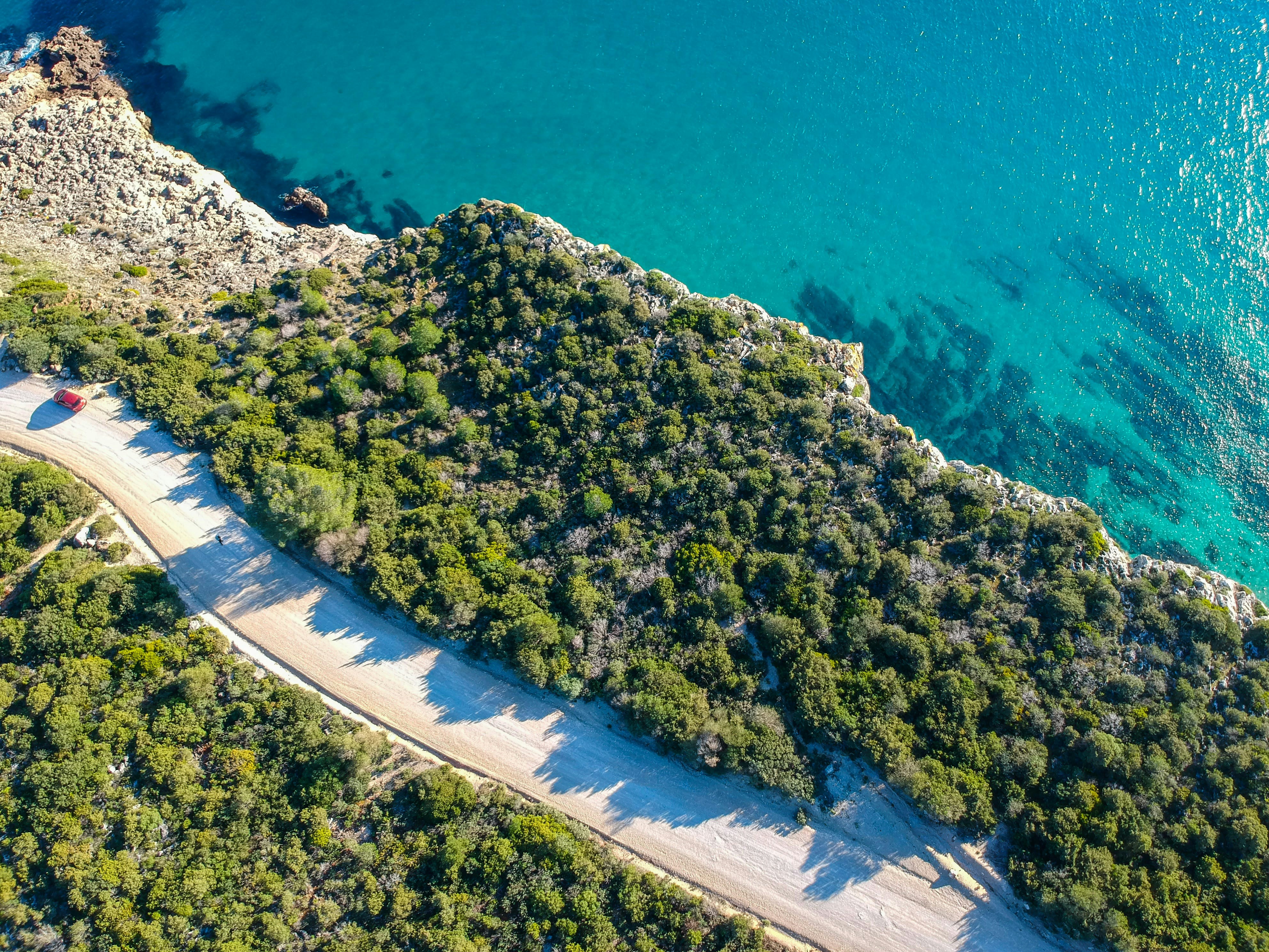 an aerial view of a road next to a body of water