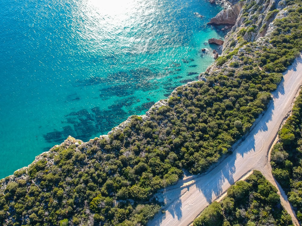 an aerial view of a road next to a body of water