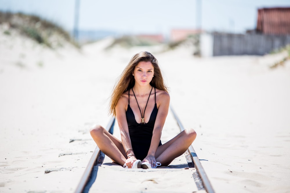 a beautiful young woman sitting on top of a train track