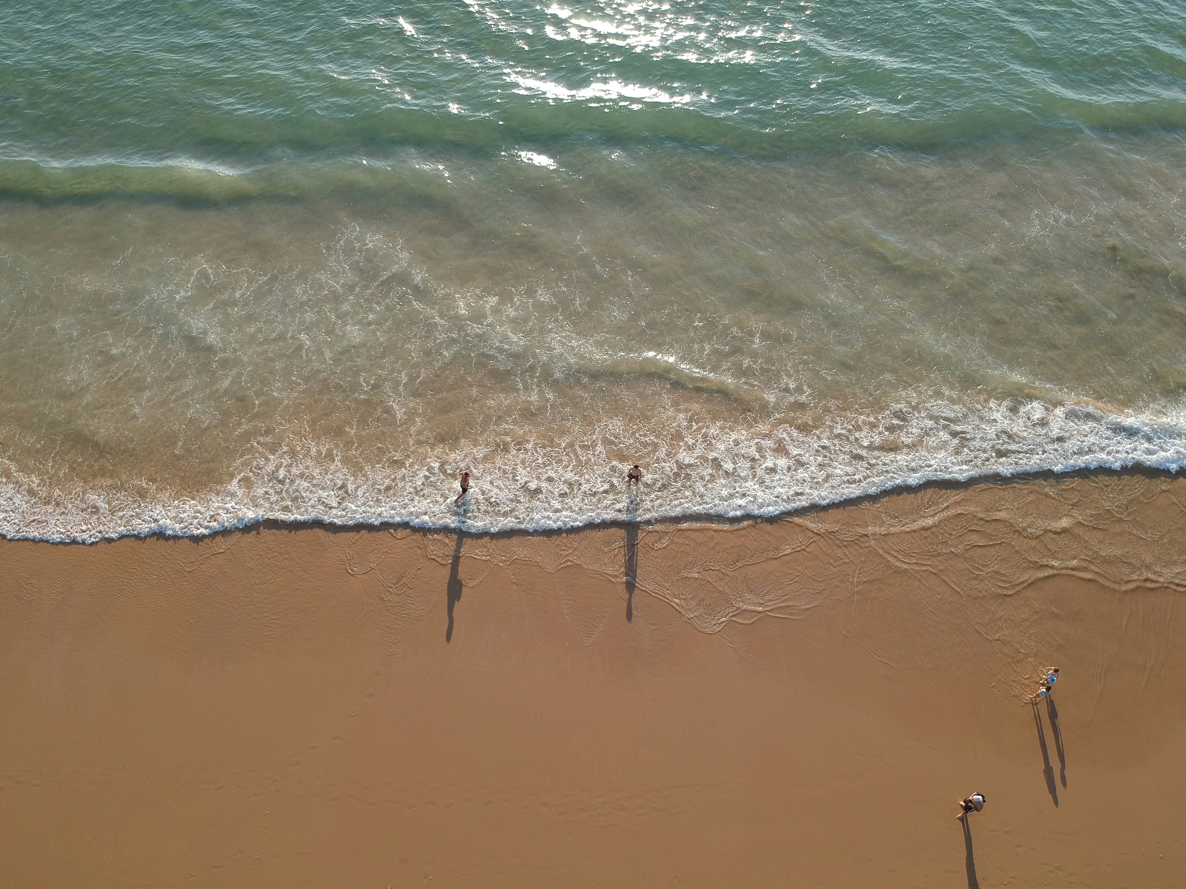 two people standing on a beach next to the ocean